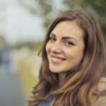 A young woman smiling warmly with a blurred outdoor background in Budapest.